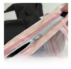 Detailed view of the smooth metal zipper closure on the striped canvas tote bag