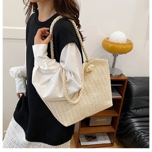 Detail of beige straw woven tote bag featuring thick cotton rope handles and V-shaped texture