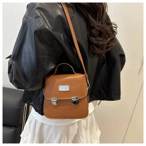 Borsa a tracolla marrone in similpelle con fibbie argentate indossata da modella