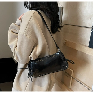 Detail der schwarzen Lackleder-Tasche mit seitlichen Schleifen und silbernen Nieten
