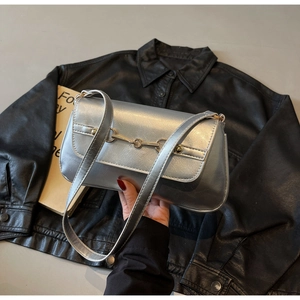 Détail du sac baguette argenté métallisé avec boucle mors dorée sur fond sombre