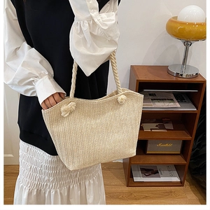 Detail shot of beige straw tote bag featuring thick rope handles and woven texture