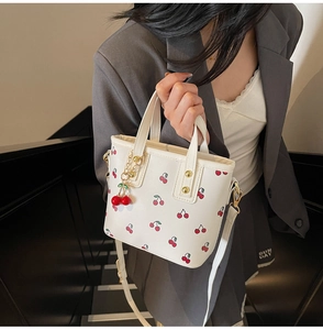 Detailed side view of off-white cherry print tote bag with 3D cherry charm and gold studs