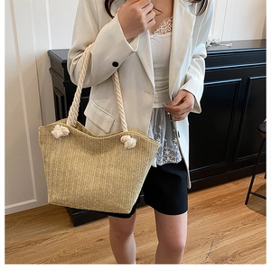 Detail of woven straw tote bag featuring rope handles and a beige herringbone pattern
