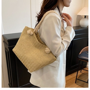 Natural straw tote bag with woven rope handles and herringbone pattern texture detail