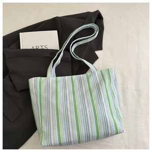 Detail of green and purple striped seersucker tote bag on a textured background