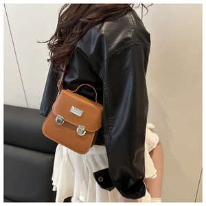 Brown retro square handbag detail with silver metal buckles on matte leather strap