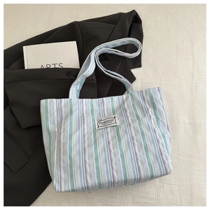 Detail of colorful striped canvas tote bag showing textile texture and fashion label
