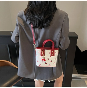 Detail shot of cherry print crossbody bag worn with grey blazer for daily outfit