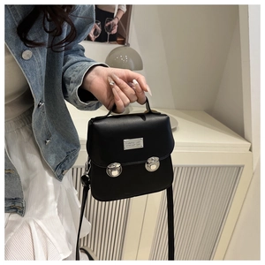 Detail of a vintage black leather bucket bag with silver push locks and a top handle