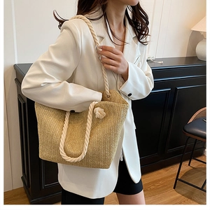 Straw handbag with cream rope handles shown against a modern white outfit
