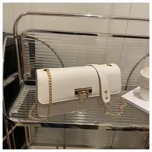 Détail du sac en cuir crème élégant avec boucle dorée et bandoulière en chaîne dorée