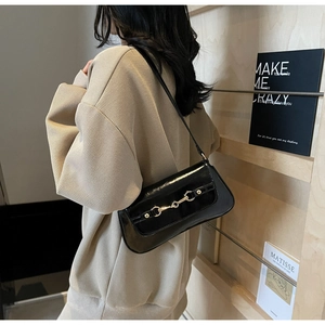 Détail d'un sac à bandoulière en cuir verni noir avec boucle mors dorée élégante