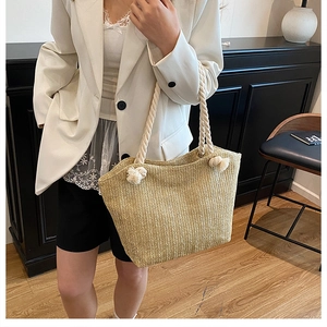 Detailed view of woven straw tote bag with knotted rope handles and natural texture