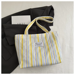 Detail of colorful striped canvas tote bag showing the fabric texture and fashion label
