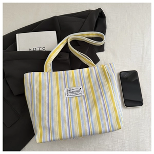 Detail of striped canvas tote bag showing the fashion label and soft fabric texture