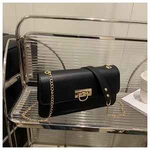Détail d'un sac rectangulaire en cuir noir avec boucle dorée en U et bandoulière chaîne