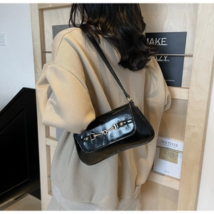 Détail du sac d'épaule en cuir verni noir avec boucle en métal mors doré décorative