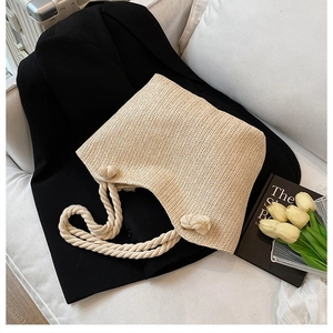 Detail of hand-woven straw tote with thick cotton rope handles and decorative knit balls