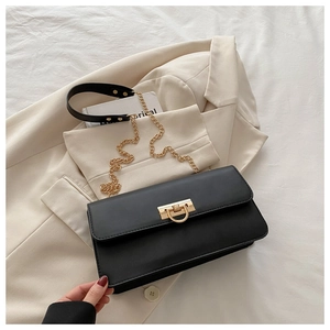 Détail d'un sac rectangulaire noir vintage avec chaîne dorée et fermoir rotatif chic