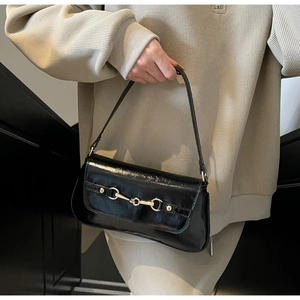 Gros plan détaillé d'un sac baguette noir brillant avec boucle mors de cheval dorée
