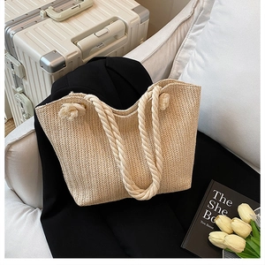 Detailed macro view of beige straw tote with herringbone weave and thick cotton rope handles