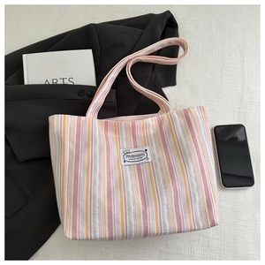 Detail of colorful striped canvas tote bag with fashion label and lifestyle props
