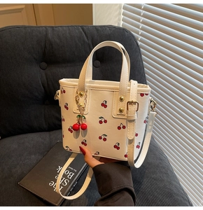 Detail of white tote bag with red cherry prints and matching 3D cherry charm accessory
