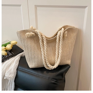 Detail of a beige woven straw tote bag with rope handles and a summer vacation aesthetic