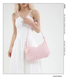 Detail of pink bubble texture bag with woven handle and flower charm on white dress