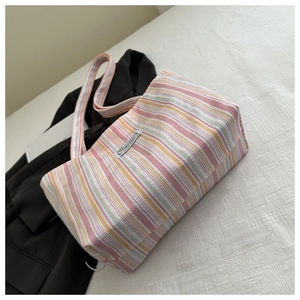 Close-up of multi-color striped canvas tote bag with detailed brand label and woven strap