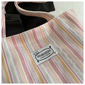 Detailed macro view of colorful striped canvas tote fabric texture and bear brand label