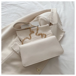 Détail du sac bandoulière en cuir beige avec chaîne dorée sur fond minimaliste