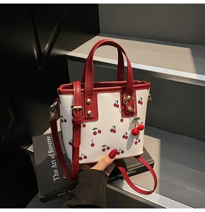Detailed close-up of cherry pattern bucket bag with red handles and cute cherry charm