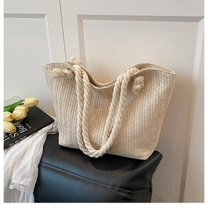 Detail of woven straw tote bag featuring wavy texture and thick cotton rope handles