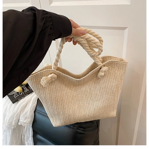 Detail of hand-woven straw tote with thick cotton rope handles and knot decoration