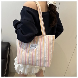 Close-up of pink and yellow vertical striped canvas tote bag with a white fashion label