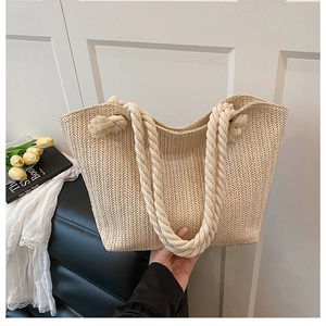 Close-up of beige straw tote bag featuring herringbone weave and cotton rope handles