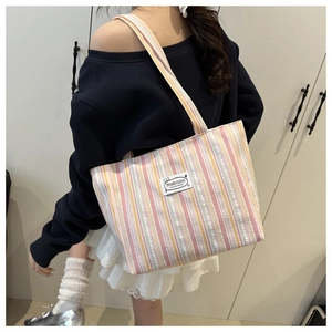 Detailed side view of large striped canvas tote bag worn over the shoulder for daily commute
