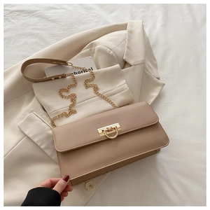Détail du sac baguette beige avec fermoir en U doré et bandoulière en cuir et chaîne