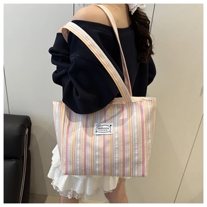Close-up of pink and yellow striped canvas tote bag with a minimalist fashion label