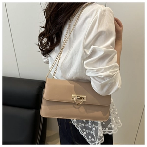 Détail du sac baguette beige avec boucle en D dorée et fine bandoulière chaîne