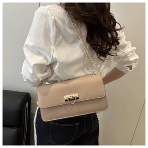 Détail du sac carré abricot avec boucle dorée et bandoulière chaîne sur une femme