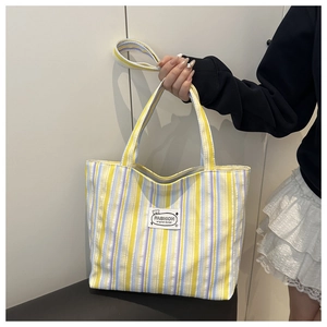 Close-up of yellow and lavender striped canvas tote bag with fashion design woven label