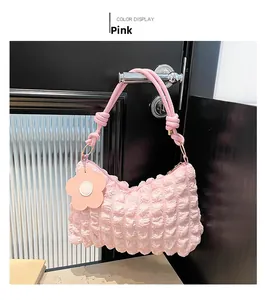 Detailed view of pink ruched crossbody bag with knotted strap and floral charm accessory