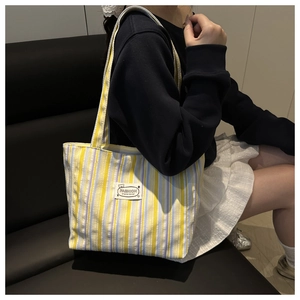 Detail of striped canvas tote bag featuring a white square fashion woven patch