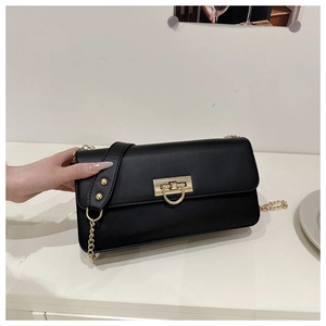 Détail du sac à bandoulière en cuir noir avec fermoir doré et bandoulière chaîne