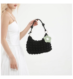 Detail of black textured bubble hobo bag with knotted leather handle and flower charm