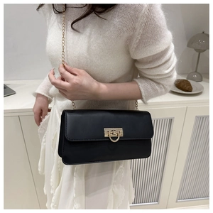Détail d'un sac bandoulière en cuir noir avec fermoir en D doré et bandoulière chaîne