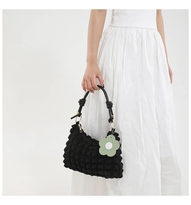 Detail of black bubble texture shoulder bag with knot handle and floral charm